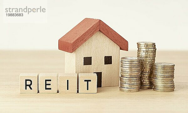 REIT Real Estate Investment Trust Konzept. Hausmodell  Geld und Holzblöcke mit Text