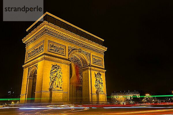 Ein Bild des Arc de Triomphe  beleuchtet mit Autos in der Nähe  bei Nacht (Paris)