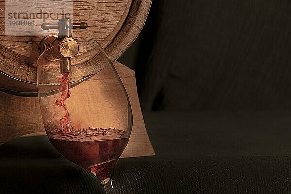 Einschenken von Wein in ein Glas aus einem Eichenfass  eine Panorama Nahaufnahme auf einem dunklen Hintergrund mit Platz für Text  getöntes Bild