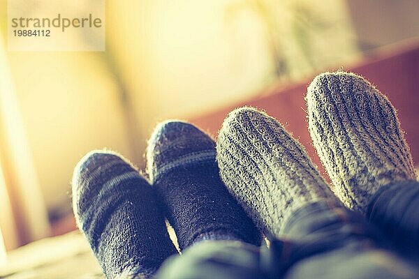 Füße mit Wollsocken in der Winterzeit: Pärchen entspannt auf der Couch