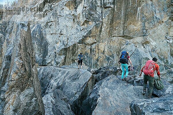 Bergsteiger bereiten sich auf den Aufstieg vor. Drei männliche und weibliche Personen gehen auf den Felsen. Extremer Outdoor Sport