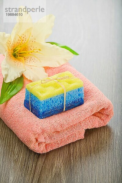 Badeschwamm Seife und Blume auf Handtuch