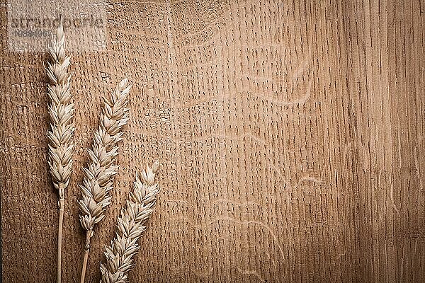 Drei Ähren reifen Weizens auf hölzernem Hintergrund horizontale Version