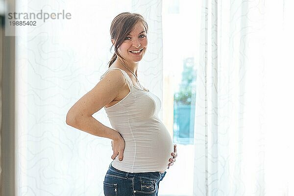 Glückliche kaukasische schwangere Mutter  die ihren Bauch berührt  Blue Jeans  Nahaufnahme