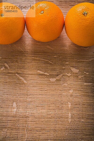 Drei orangefarbene Früchte auf Holztisch mit organisiertem Kopierbereich