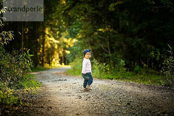 Porträt eines 2 Jahre alten Mädchens im Wald  das alleine spazieren geht. Möchte den Eltern nicht folgen. Konzept der Unabhängigkeit des Kindes