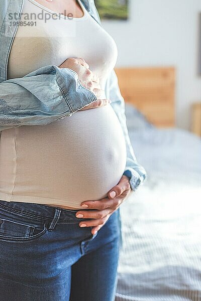 Kaukasische schwangere Mutter  die ihren nackten Bauch berührt  Blue Jeans  Nahaufnahme