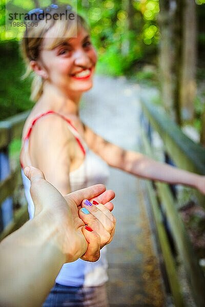 Junges Mädchen hält ihre Hand zu ihrem Freund  draußen im Wald