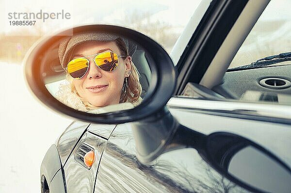 Hipster Frau mit Sonnenbrille sitzt in einem kleinen Auto im Winter