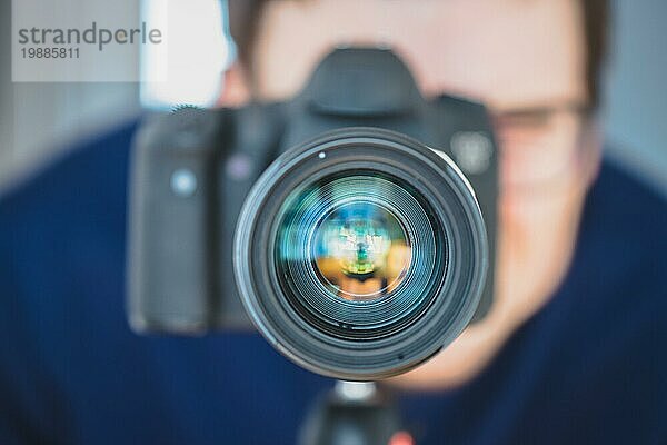 Der Fotograf steht hinter einer professionellen Kamera mit Teleobjektiv auf einem Stativ