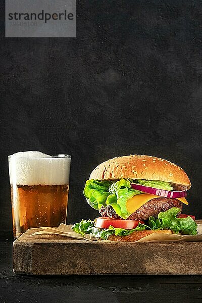 Burger und Bier  eine Seitenansicht auf einem dunklen Hintergrund mit Kopierraum. Selektiver Fokus