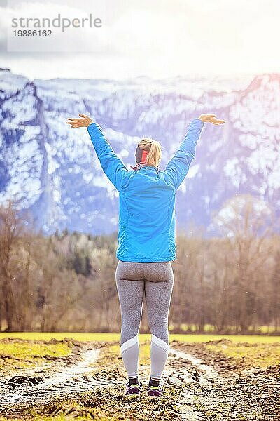 Mädchen in blaür und grauer Sportkleidung steht auf einem Feld und macht eine wunderbare Geste