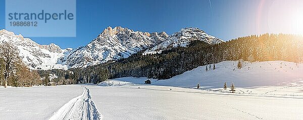 Schöne idyllische Winterlandschaft mit Wanderweg  atemberaubender Bergkette  verschneiten Bäumen und blauem Himmel