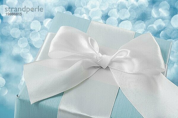 Draufsicht blaue Geschenkbox mit weißer Schleife auf unscharfem Hintergrund