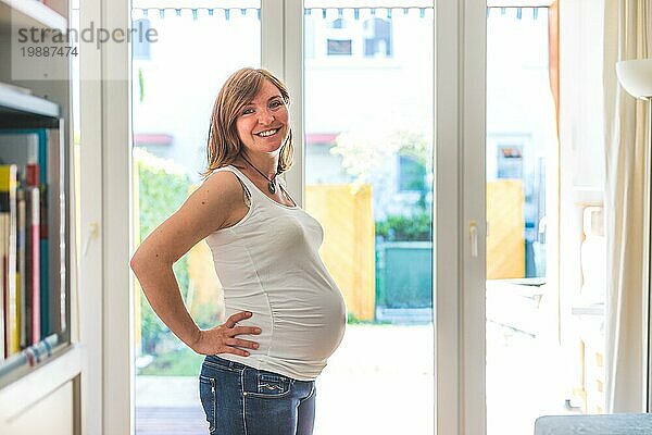 Glückliche kaukasische schwangere Mutter  die ihren Bauch berührt  Blue Jeans  Nahaufnahme