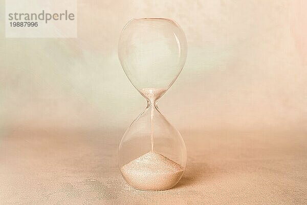 Die Zeit. Ein Stundenglas mit Sand  der durchfällt. Alter  Nostalgie Konzept  sepia getöntes Bild