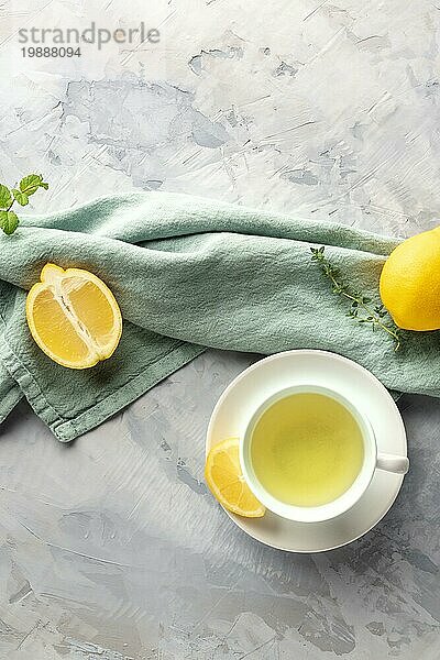 Eine Tasse grüner Tee mit Zitronen und Kräutern  aufgenommen von oben mit Kopierraum. Natürliche Heilmittel gegen Erkältung