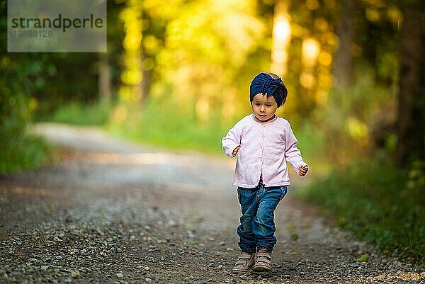 Porträt eines 2 Jahre alten Mädchens im Wald  das alleine spazieren geht. Möchte den Eltern nicht folgen. Konzept der Unabhängigkeit des Kindes