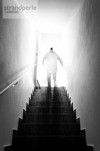 Ein Mann geht eine Kellertreppe mit Geländer hinauf. Natürliches helles Sonnenlicht
