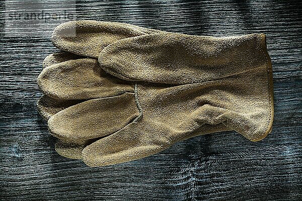 Schutzhandschuhe aus Leder auf Holzplatte Draufsicht