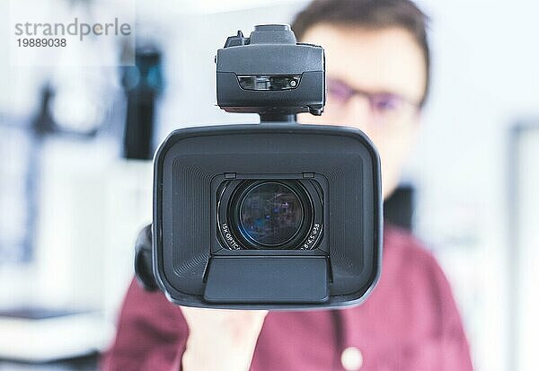 Männlicher Kameramann hält einen professionellen Video Camcorder  unscharfer Hintergrund