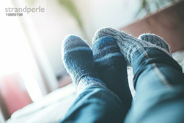 Füße mit Wollsocken in der Winterzeit: Pärchen entspannt auf der Couch