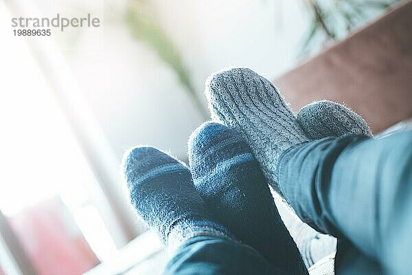 Füße mit Wollsocken in der Winterzeit: Pärchen entspannt auf der Couch