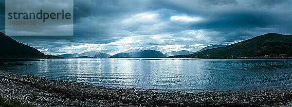 Schöne mystische Landschaft Seelandschaft in Schottland mit bewölktem Himmel und Sonnenstrahlen