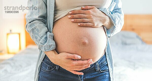 Kaukasische schwangere Mutter  die ihren nackten Bauch berührt  Blue Jeans  Nahaufnahme