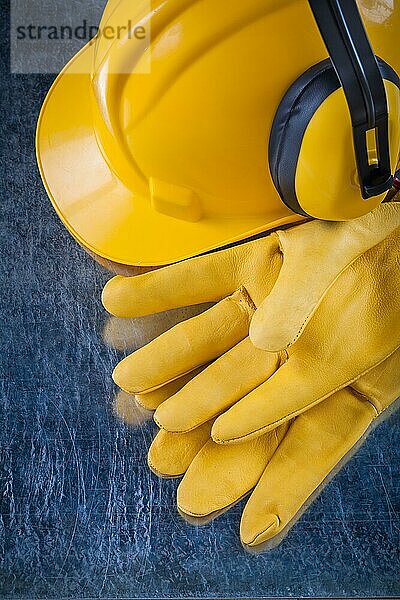Hard Hut Sicherheit Ohrenschützer und gelbe Leder Schutzhandschuhe auf metallischen Hintergrund Bau Konzept