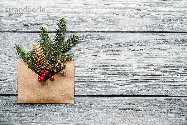 Nachhaltige Weihnachten  natürliche plastikfreie Dekoration in Papierumschlag auf hölzernem Hintergrund  Kopierraum