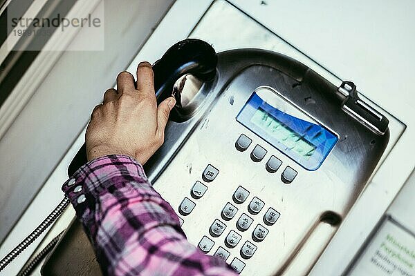 Junge Frau spricht mit einem klassischen  altmodischen Münztelefon