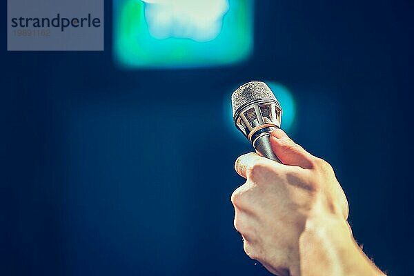 Person hält ein Metallmikrofon in der Hand und will jemanden interviewen  Raum kopieren