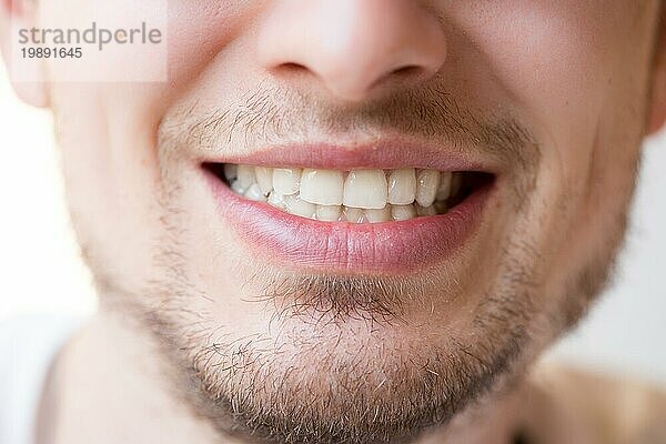 Junger Mann mit weißen Zähnen  roten Lippen und einem Bart lächelt