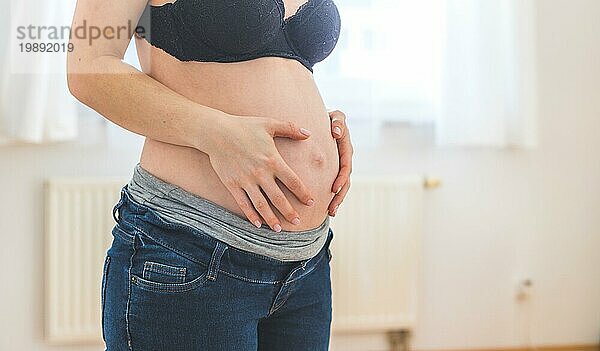 Nahaufnahme einer schwangeren kaukasischen Mutter  die ihren nackten Bauch berührt