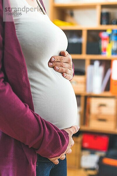 Nahaufnahme eines schwangeren Bauches  kaukasische Mutter mit weißem Hemd und magentafarbener Jacke