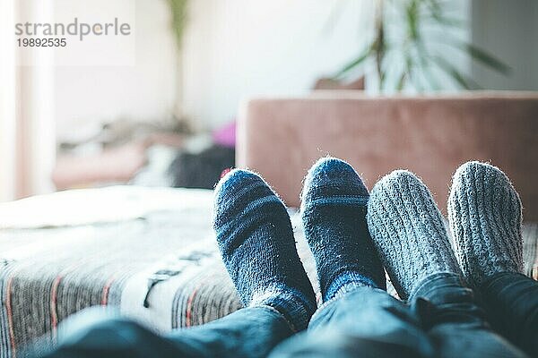 Füße mit Wollsocken in der Winterzeit: Pärchen entspannt auf der Couch