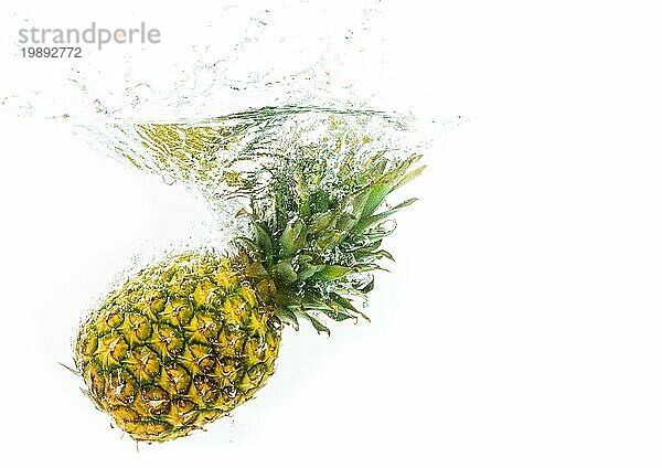 Ananas wird in klares Wasser fallen gelassen  vor weißem Hintergrund. Obst spritzen Thema mit Kopie Raum