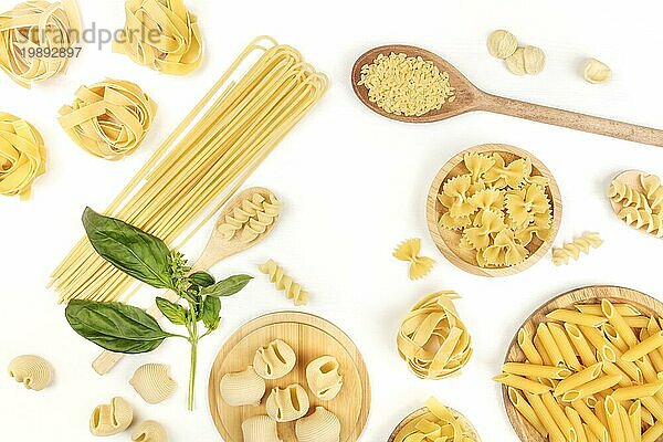 Ein Overhead Foto von verschiedenen Arten von Nudeln  einschließlich Spaghetti  Penne  Fusilli  und andere  mit frischem Basilikum Blätter  die einen Rahmen  Schuss von oben auf einem weißen Hintergrund mit Kopie Raum