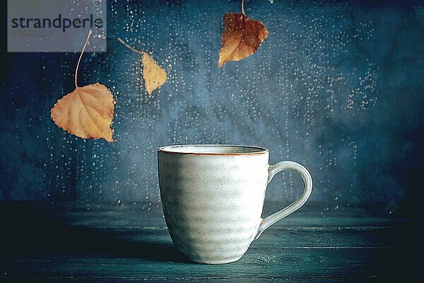 Regentag mit einer Tasse Tee. Herbstblätter  Regen hinter dem Fenster  ein warmes Getränk