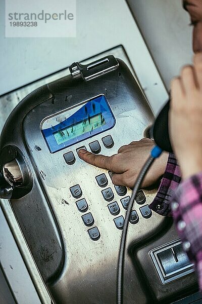 Junge Frau spricht mit einem klassischen  altmodischen Münztelefon