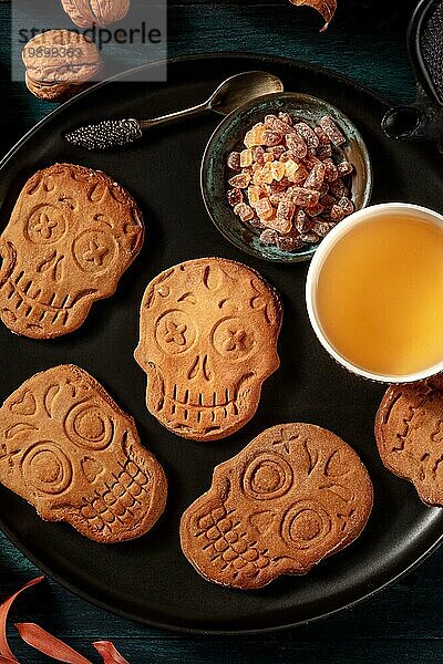 Halloween Ingwer Kekse in Form von Totenköpfen  hausgemachte Dia de los muertos Kekse  Overhead Aufnahme auf einem dunklen Holzhintergrund