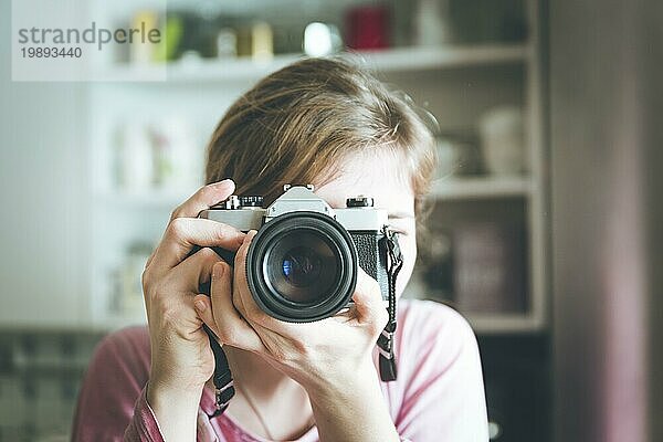 Junges Mädchen macht ein Foto mit einer alten Kamera