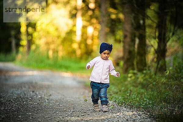 Porträt eines 2 Jahre alten Mädchens im Wald  das alleine spazieren geht. Möchte den Eltern nicht folgen. Konzept der Unabhängigkeit des Kindes