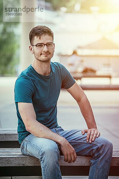 Männlicher junger Angestellter sitzt im Freien und macht eine Pause. Porträtaufnahme