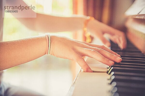 Junges Mädchen übt zu Hause am Klavier. Ausschnitt von Klavier und Händen