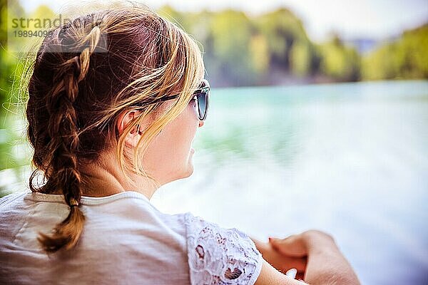 Schöne junge Frau sitzt an einem See und genießt den Tag