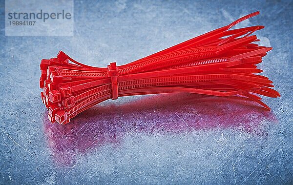 Rote selbstverriegelnde Kabelbinder aus Kunststoff auf metallischem Hintergrund Konstruktionskonzept