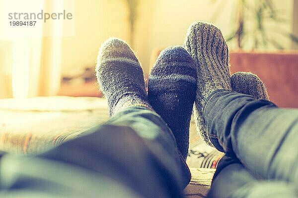 Füße mit Wollsocken in der Winterzeit: Pärchen entspannt auf der Couch