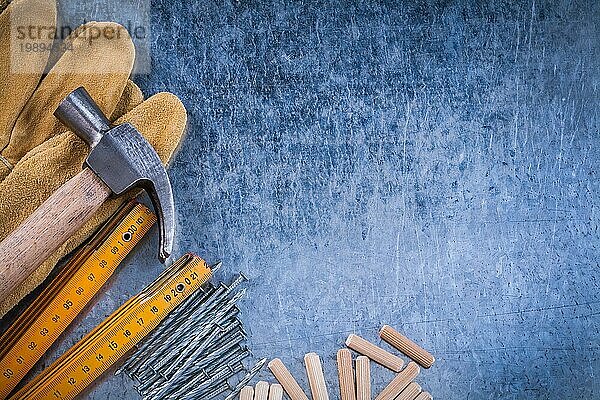 Zusammensetzung der Hammer Sicherheitshandschuhe hölzernen Meter rostfreie Nägel und Dübel auf zerkratzte metallische Oberfläche Baukonzept